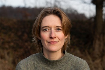 Porträtfoto von einer Frau mit kurzen Haaren, draußen in der Natur